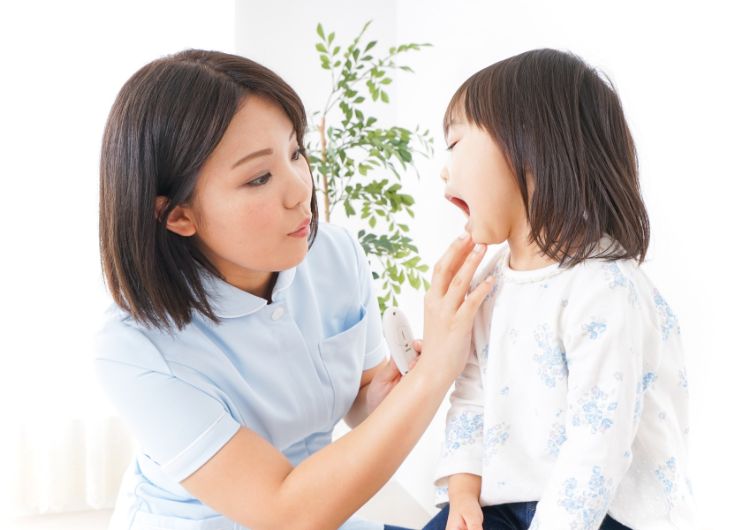 衛生士が子どもの口の中を見ている