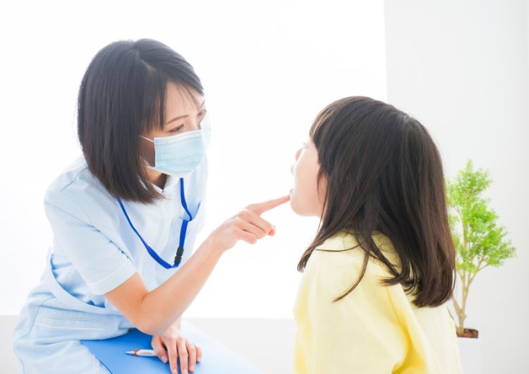 歯科衛生士が女の子の口の中を確認する写真