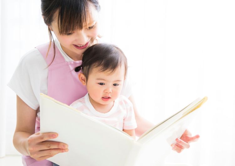 保育士に絵本を読んでもらう子ども